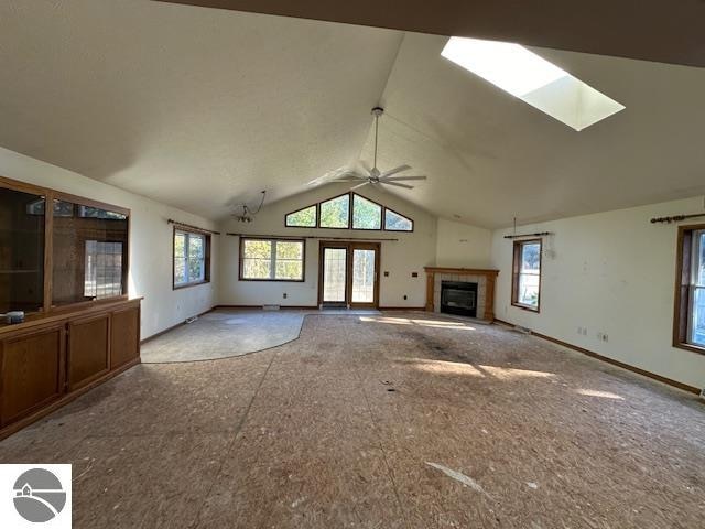 unfurnished living room with lofted ceiling with skylight, ceiling fan, and french doors