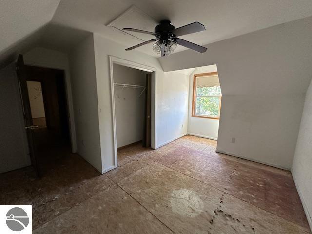 unfurnished bedroom featuring a closet, lofted ceiling, and ceiling fan