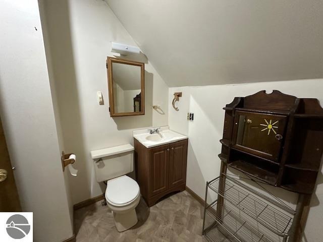 bathroom featuring vanity, lofted ceiling, and toilet