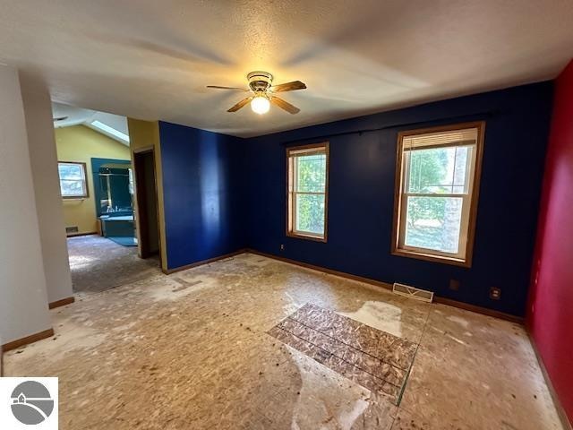 unfurnished room with a textured ceiling, vaulted ceiling, and ceiling fan