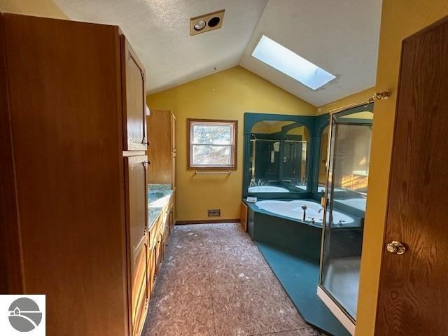 bathroom with a textured ceiling, lofted ceiling with skylight, and a bathing tub