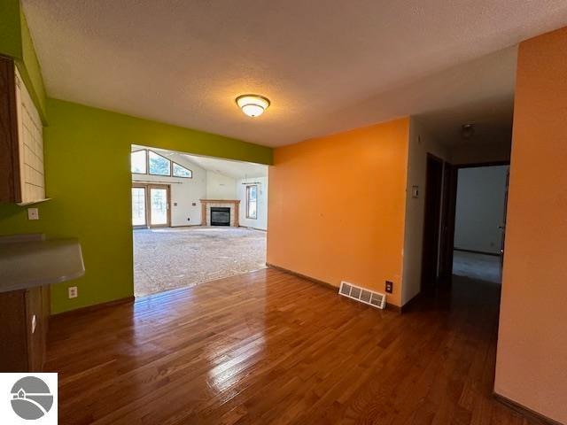 unfurnished living room with a textured ceiling and dark hardwood / wood-style floors