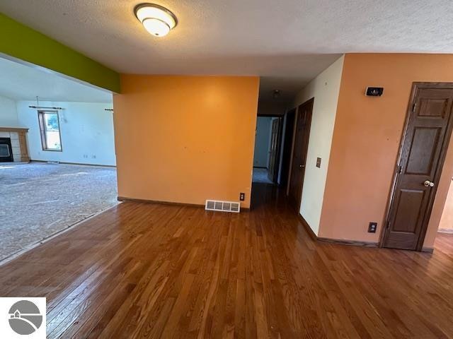 unfurnished room featuring wood-type flooring, a textured ceiling, and a fireplace