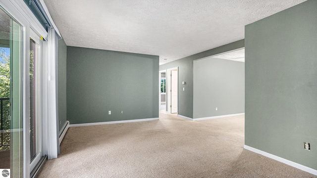 carpeted spare room featuring a textured ceiling, a baseboard heating unit, and a healthy amount of sunlight