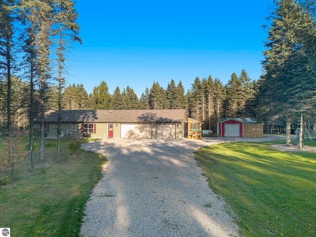 ranch-style house featuring a front yard, a garage, and an outbuilding