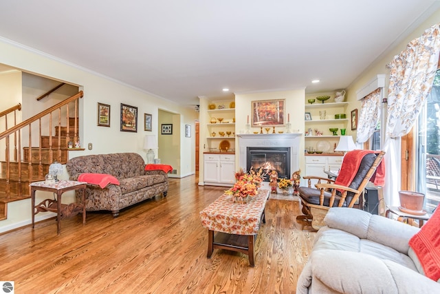 living room with ornamental molding, light wood-type flooring, and built in features