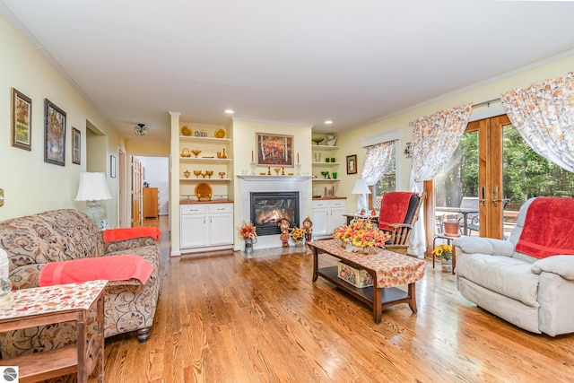 living room with light hardwood / wood-style flooring, ornamental molding, built in shelves, and french doors