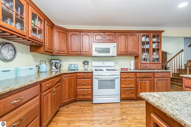 kitchen with light stone counters, light wood-type flooring, crown molding, and white appliances