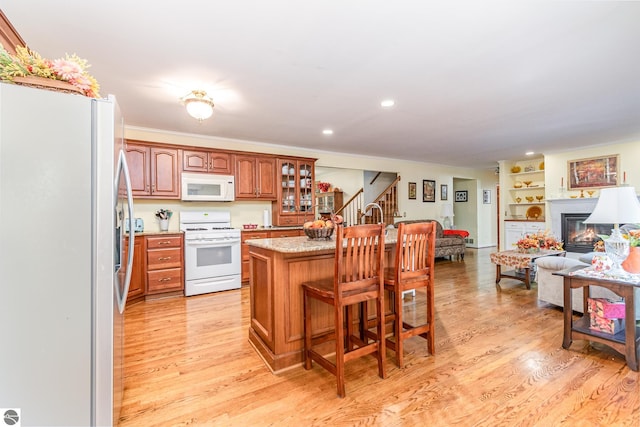 kitchen with light hardwood / wood-style flooring, white appliances, a center island, and a kitchen breakfast bar