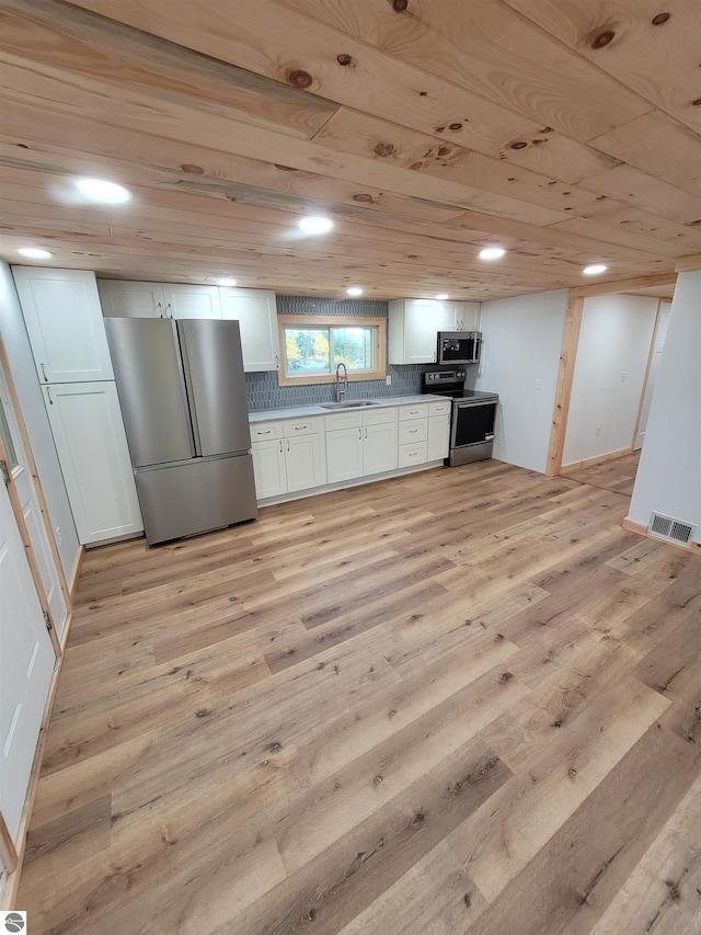 kitchen with stainless steel appliances, white cabinets, and light wood-type flooring