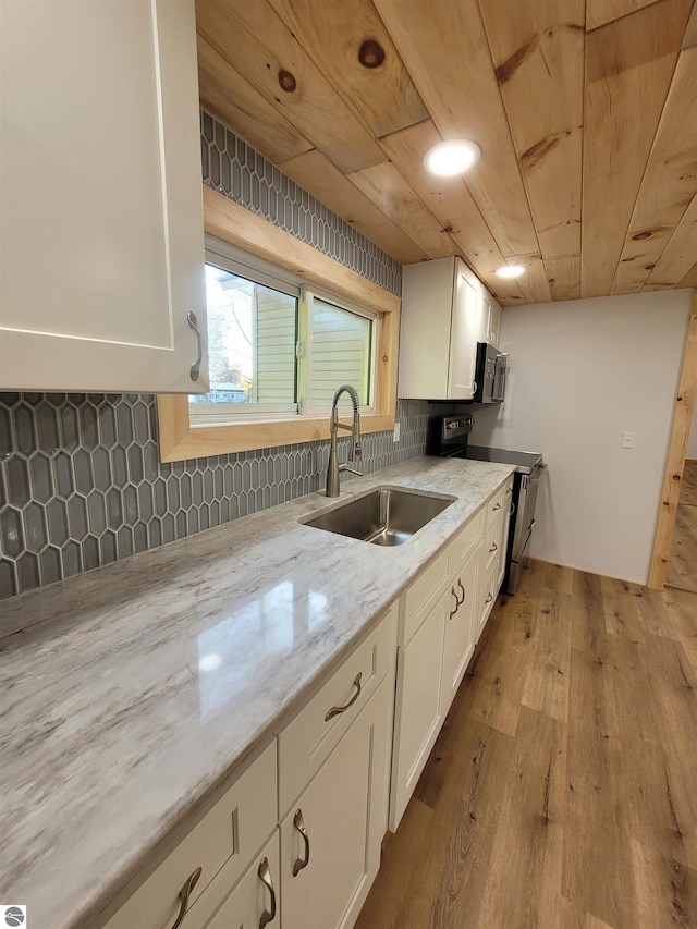 kitchen with light hardwood / wood-style floors, sink, stainless steel appliances, and white cabinets