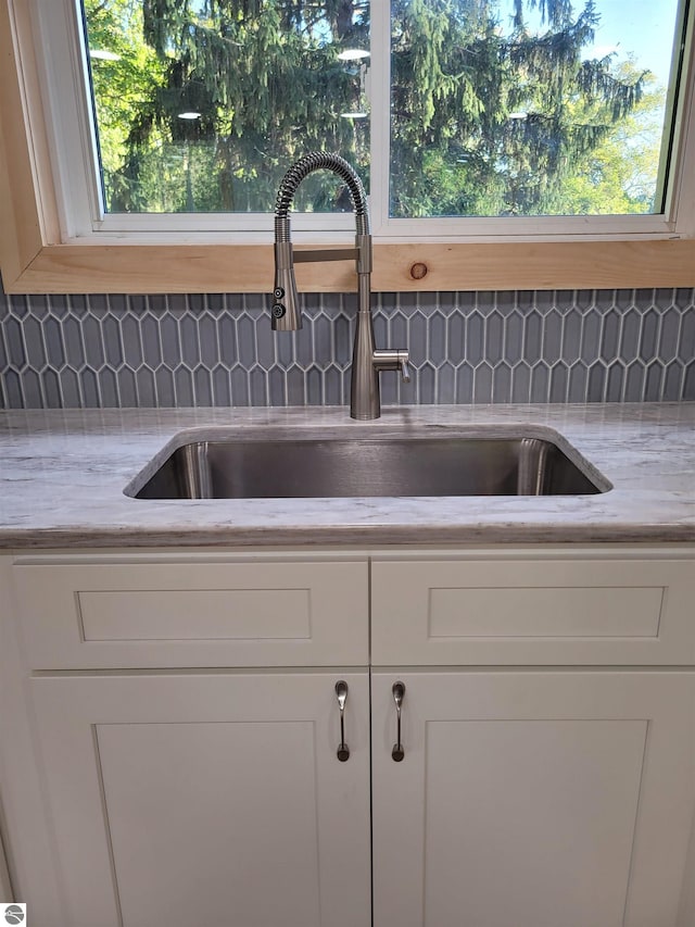 details featuring sink, white cabinetry, and decorative backsplash