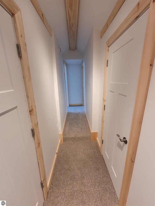 hallway with light carpet and beamed ceiling