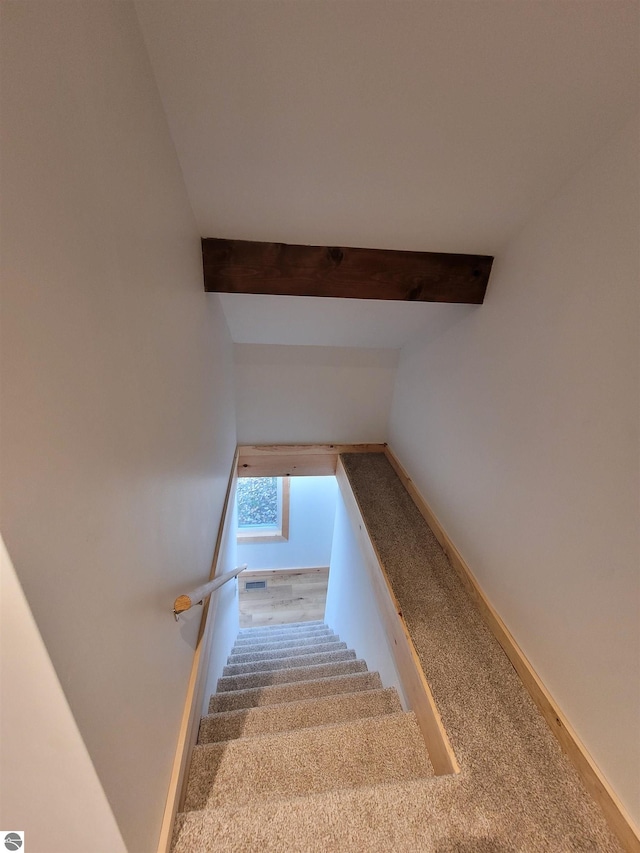 stairway featuring vaulted ceiling with beams and carpet flooring