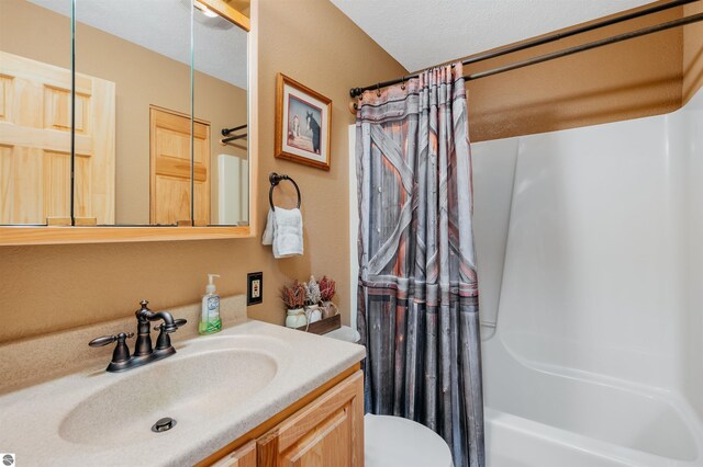 full bathroom with vanity, a textured ceiling, shower / tub combo, and toilet