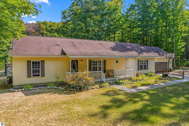 ranch-style house featuring covered porch, a front yard, and a garage