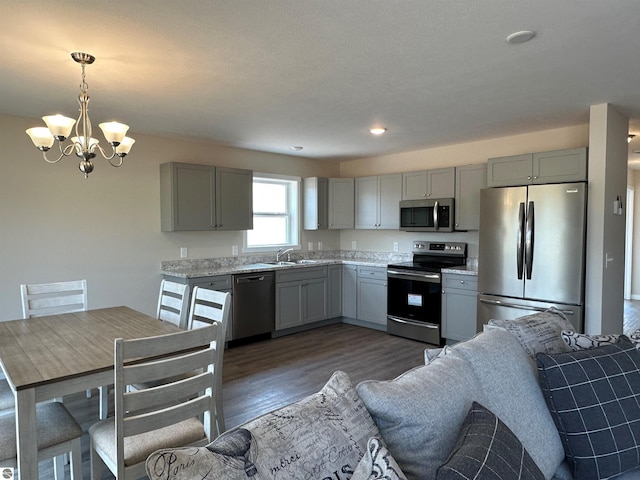 kitchen featuring appliances with stainless steel finishes, gray cabinetry, dark hardwood / wood-style floors, and decorative light fixtures