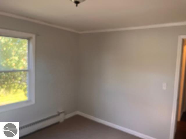 spare room with baseboard heating and ornamental molding