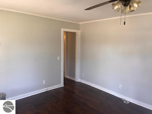 empty room with ceiling fan, ornamental molding, and dark hardwood / wood-style flooring