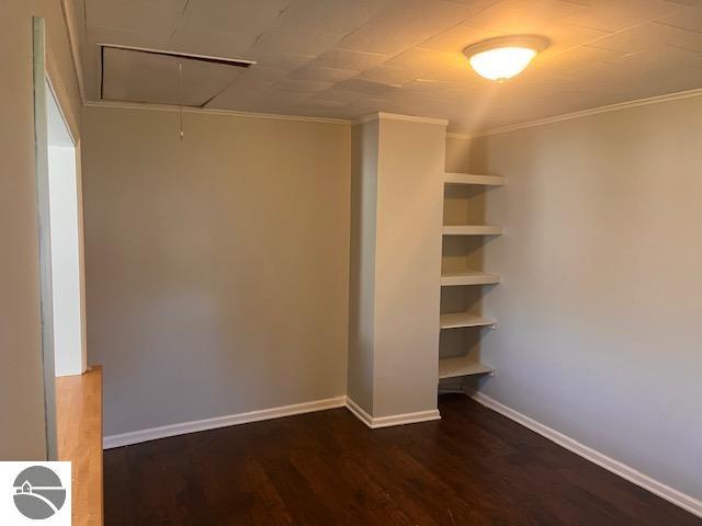 unfurnished bedroom featuring crown molding and dark hardwood / wood-style flooring