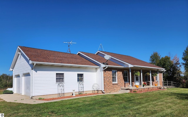 rear view of house featuring covered porch, a garage, and a lawn