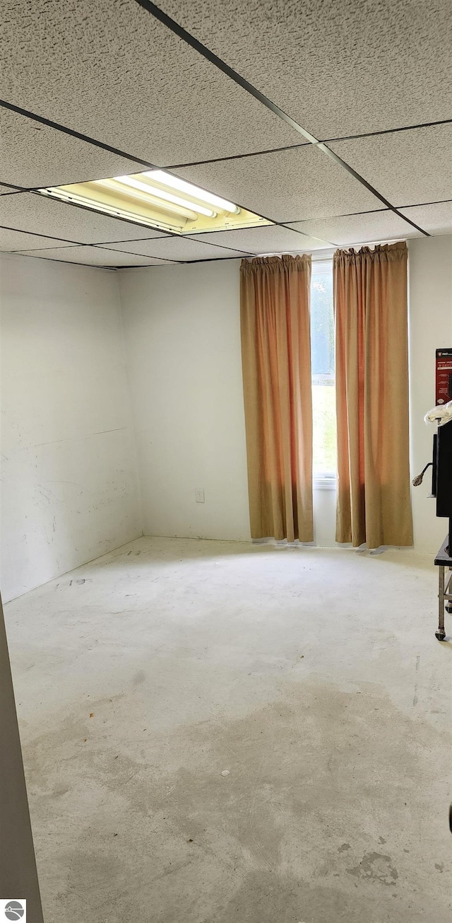 spare room featuring concrete flooring and a drop ceiling