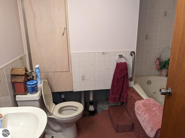 bathroom with tile walls, a bathing tub, toilet, and sink