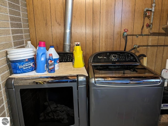 clothes washing area featuring washer / dryer and brick wall