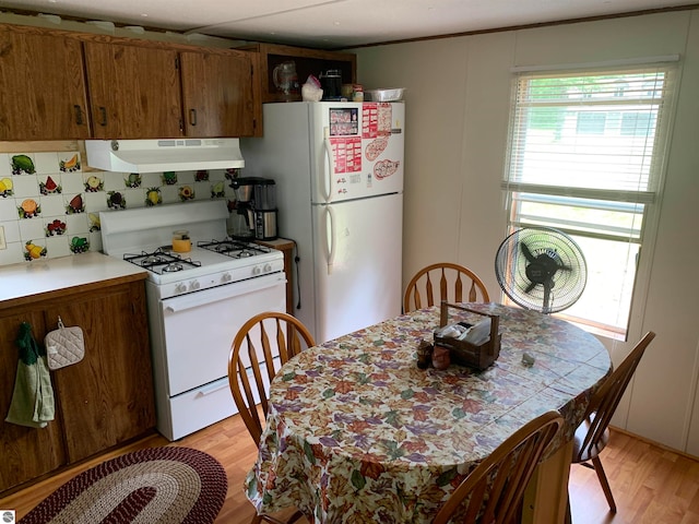 kitchen featuring decorative backsplash, light wood-type flooring, white appliances, and range hood