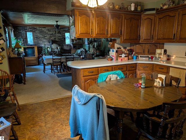 kitchen featuring light carpet, ceiling fan, and brick wall