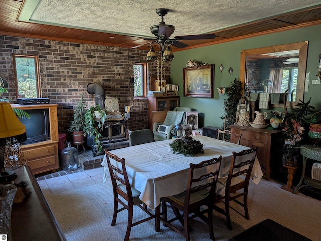 tiled dining area with ornamental molding, brick wall, a healthy amount of sunlight, and ceiling fan