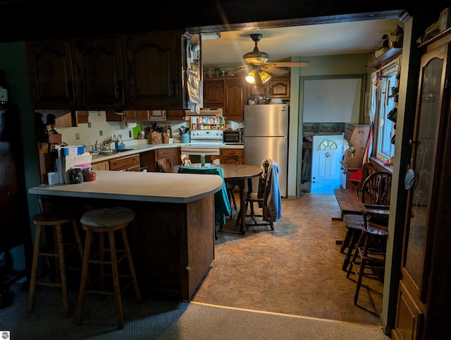 kitchen with kitchen peninsula, ceiling fan, white electric range, light colored carpet, and stainless steel fridge