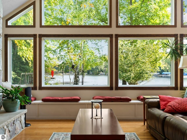 sunroom with lofted ceiling and a water view