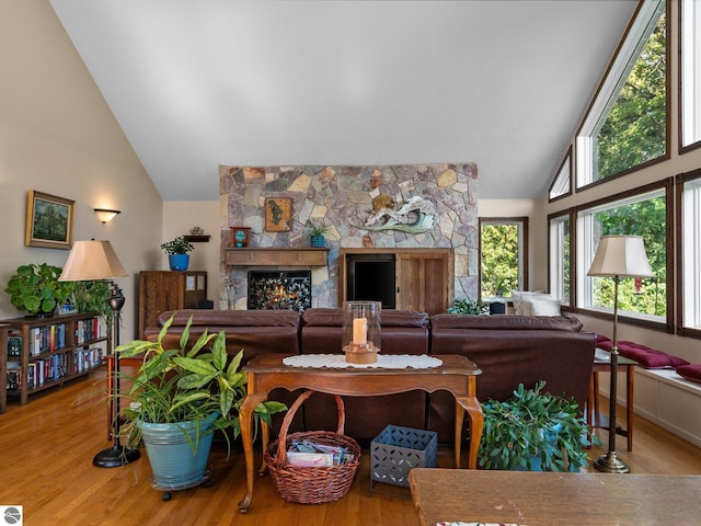 living room with a fireplace, light hardwood / wood-style floors, and high vaulted ceiling