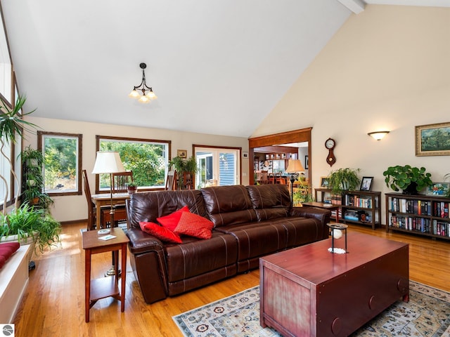 living room featuring high vaulted ceiling, an inviting chandelier, light wood-type flooring, and beamed ceiling