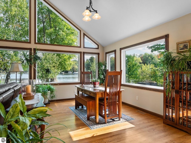 sunroom / solarium with a notable chandelier, vaulted ceiling, and a water view