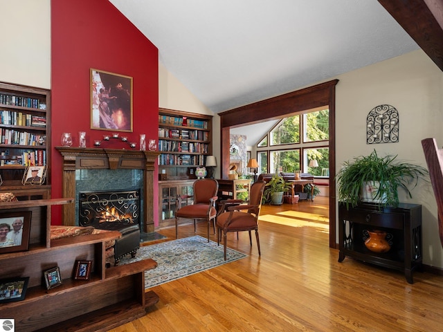 sitting room with hardwood / wood-style flooring, a high end fireplace, and high vaulted ceiling