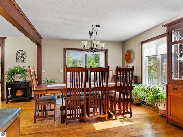 dining area featuring light wood-type flooring, a chandelier, and a textured ceiling