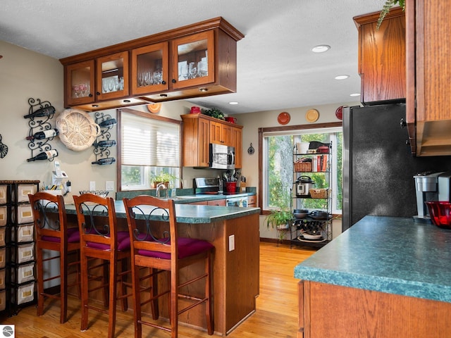 kitchen with light hardwood / wood-style flooring, stainless steel appliances, a kitchen breakfast bar, and a wealth of natural light