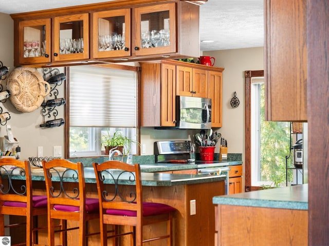 kitchen with appliances with stainless steel finishes, a kitchen breakfast bar, and a textured ceiling