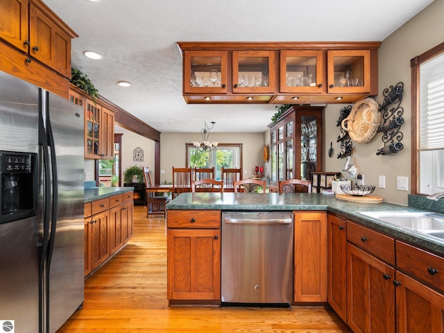 kitchen featuring stainless steel appliances, sink, light hardwood / wood-style floors, a chandelier, and a textured ceiling