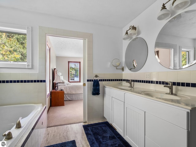 bathroom with a washtub, tile walls, hardwood / wood-style flooring, vanity, and a textured ceiling