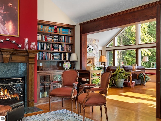 sitting room featuring wood-type flooring, a premium fireplace, and vaulted ceiling