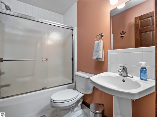 bathroom featuring shower / bath combination with glass door, toilet, a textured ceiling, tile patterned flooring, and decorative backsplash