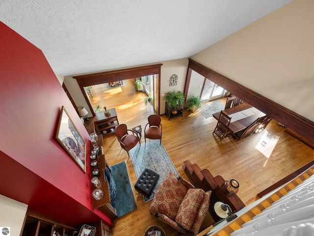 living room with hardwood / wood-style flooring, vaulted ceiling, and a textured ceiling