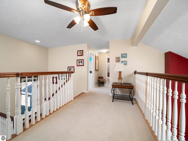 hall featuring light carpet and a textured ceiling