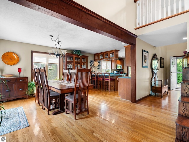 dining room with light wood-type flooring, an inviting chandelier, and a textured ceiling