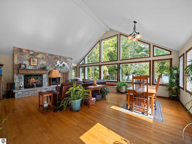 living room with a stone fireplace, beam ceiling, light hardwood / wood-style floors, and high vaulted ceiling