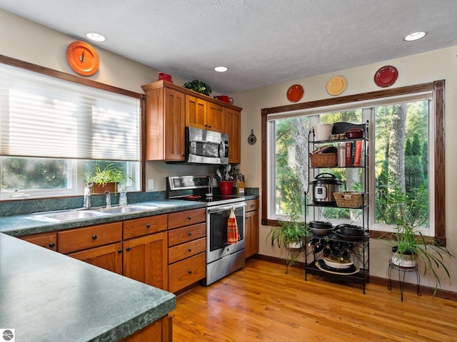 kitchen featuring stainless steel appliances, sink, light hardwood / wood-style flooring, and a textured ceiling