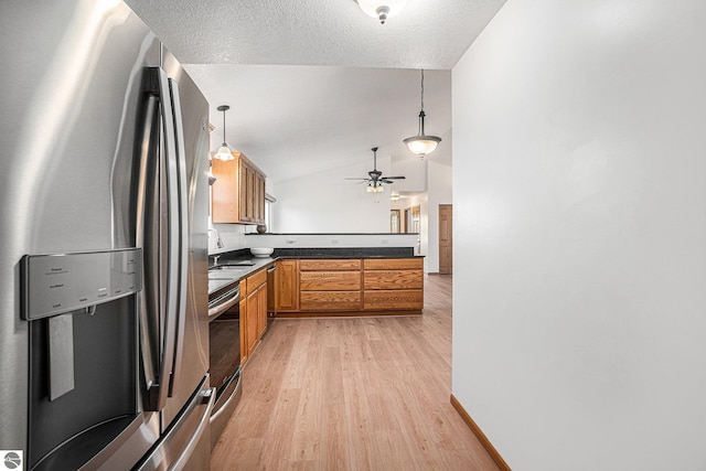 kitchen featuring stainless steel appliances, pendant lighting, lofted ceiling, and light wood-type flooring